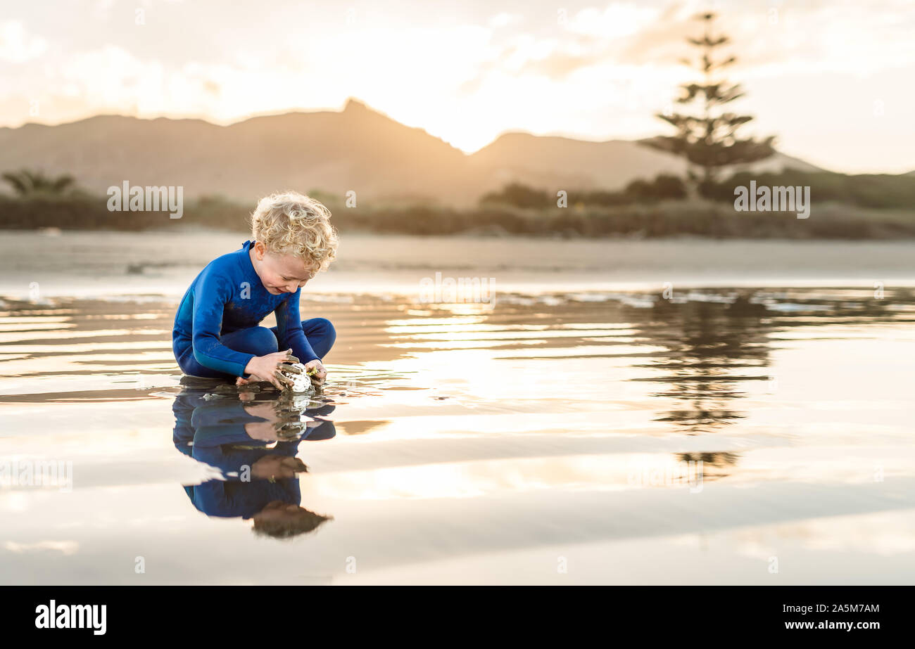 Felice preschooler a suonare in spiaggia al tramonto Foto Stock