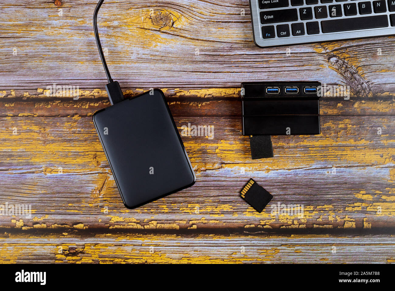 Fotografo sul posto di lavoro che copia foto da schede SD di memoria disco rigido portatile e computer portatile Foto Stock