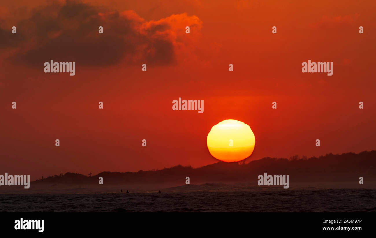 Immagine ravvicinata del tramonto sunball come salse dietro la testa sulla spiaggia vicino al surf spot di tralicci inferiori a San Clemente, la California del Sud. Foto Stock