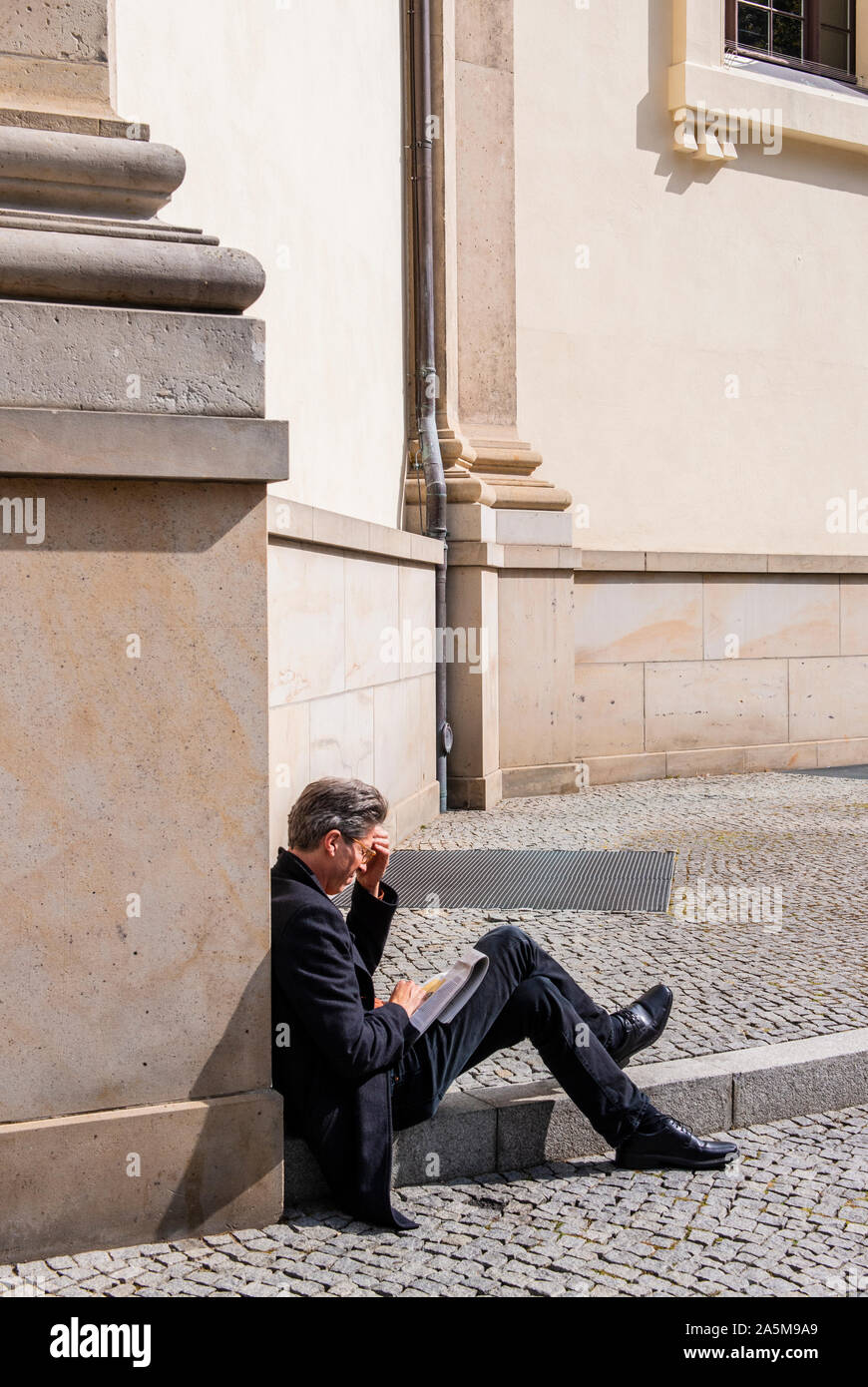 Imprenditore toccando la fronte e la scrittura su notebook sul marciapiede, Berlino, Germania, Regno Unito Foto Stock