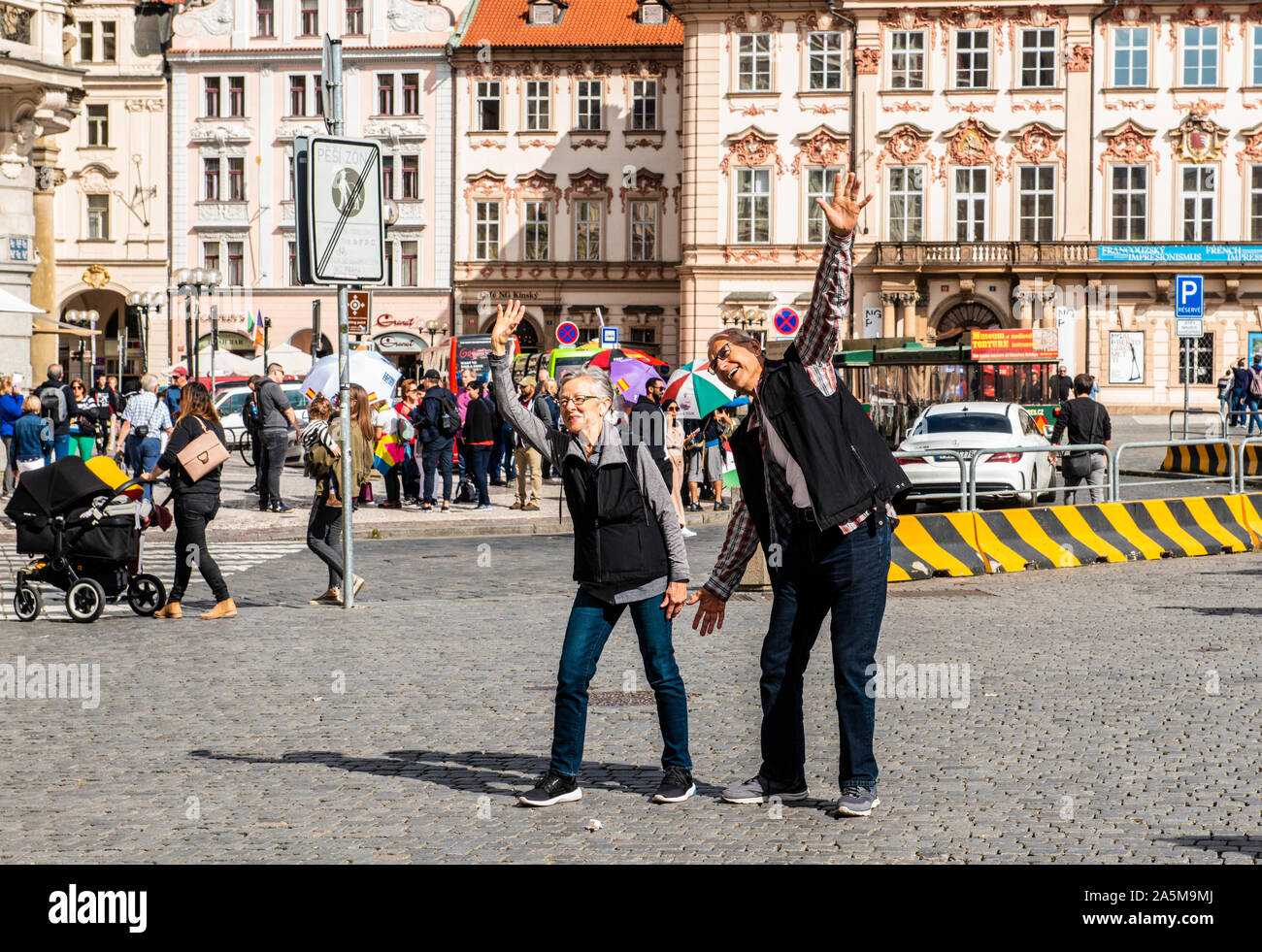 Coppia senior gesticolando e gesti sul marciapiede, Piazza della Città Vecchia di Praga, Repubblica Ceca Foto Stock