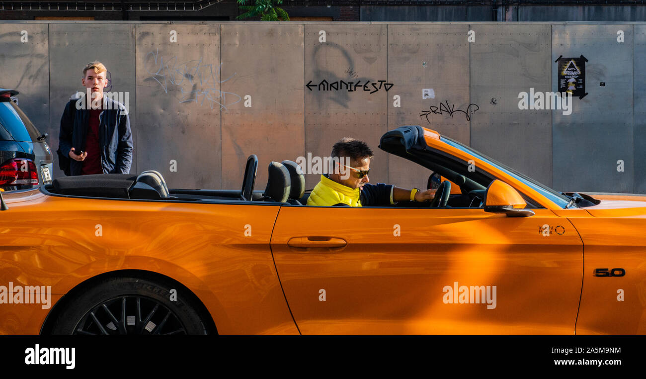 L'uomo guida convertibile arancione sulla strada, Praga, Repubblica Ceca Foto Stock
