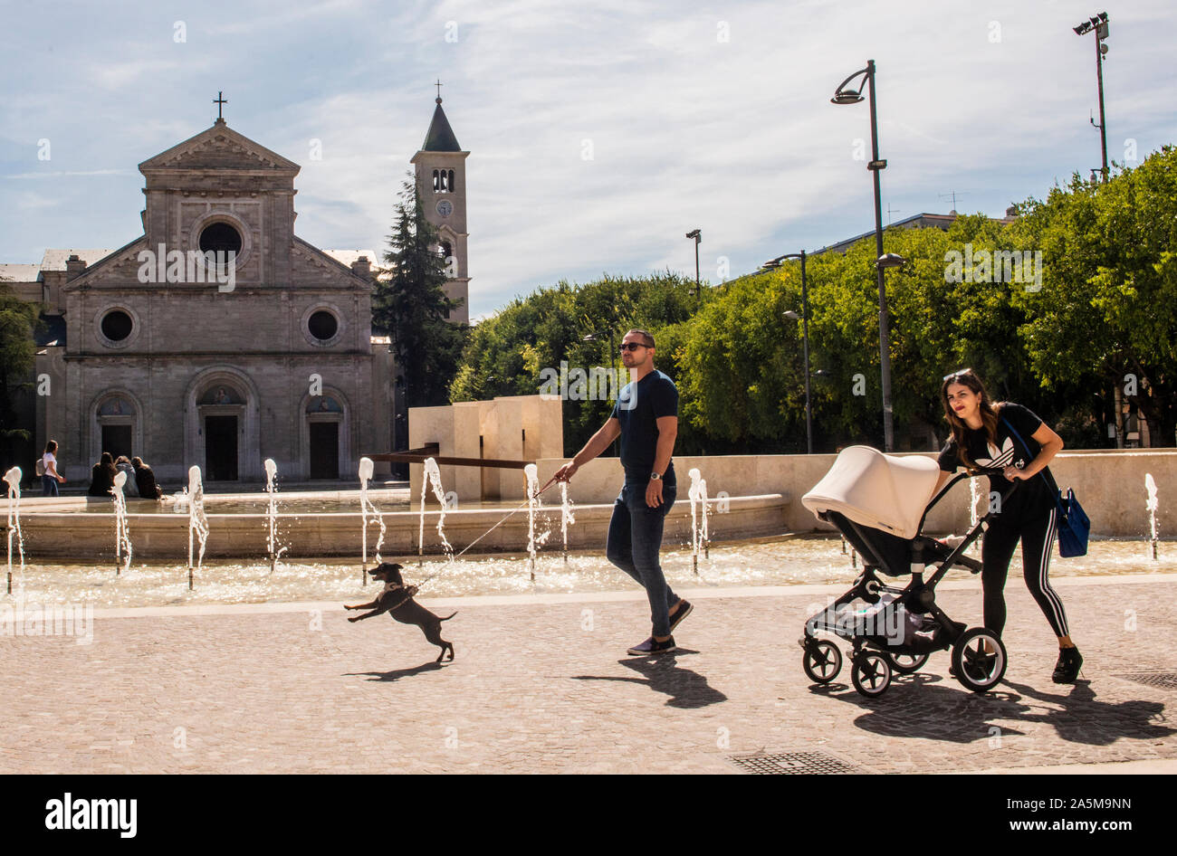 I genitori con il bambino e il cane a camminare lungo la chiesa, Piazza Risorgimento, Avezzano, Abruzzo, Italia Foto Stock