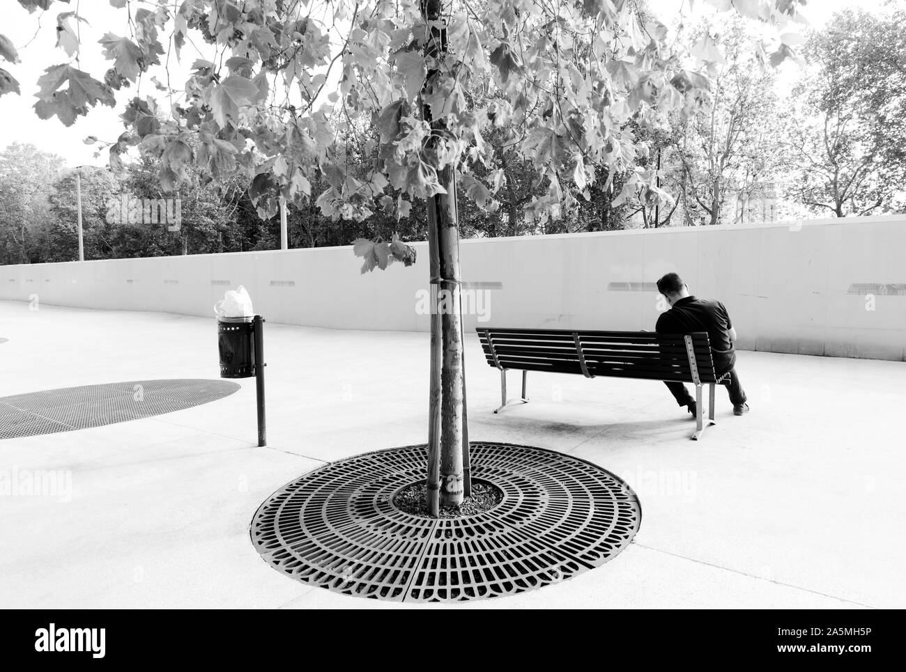 Persona seduta su una panchina in piena area urbana di calcestruzzo Foto Stock