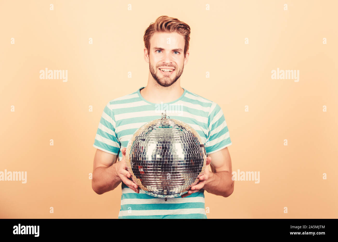 Ragazzo che vi invitano a parte. Migliaia di minuscoli specchi che riflettono la creazione delle luci di atmosfera da discoteca. Come circa la parte. Allegro dj uomo. Uomo bello tenere palla da discoteca. Danze da discoteca night club. Musica retrò. Foto Stock