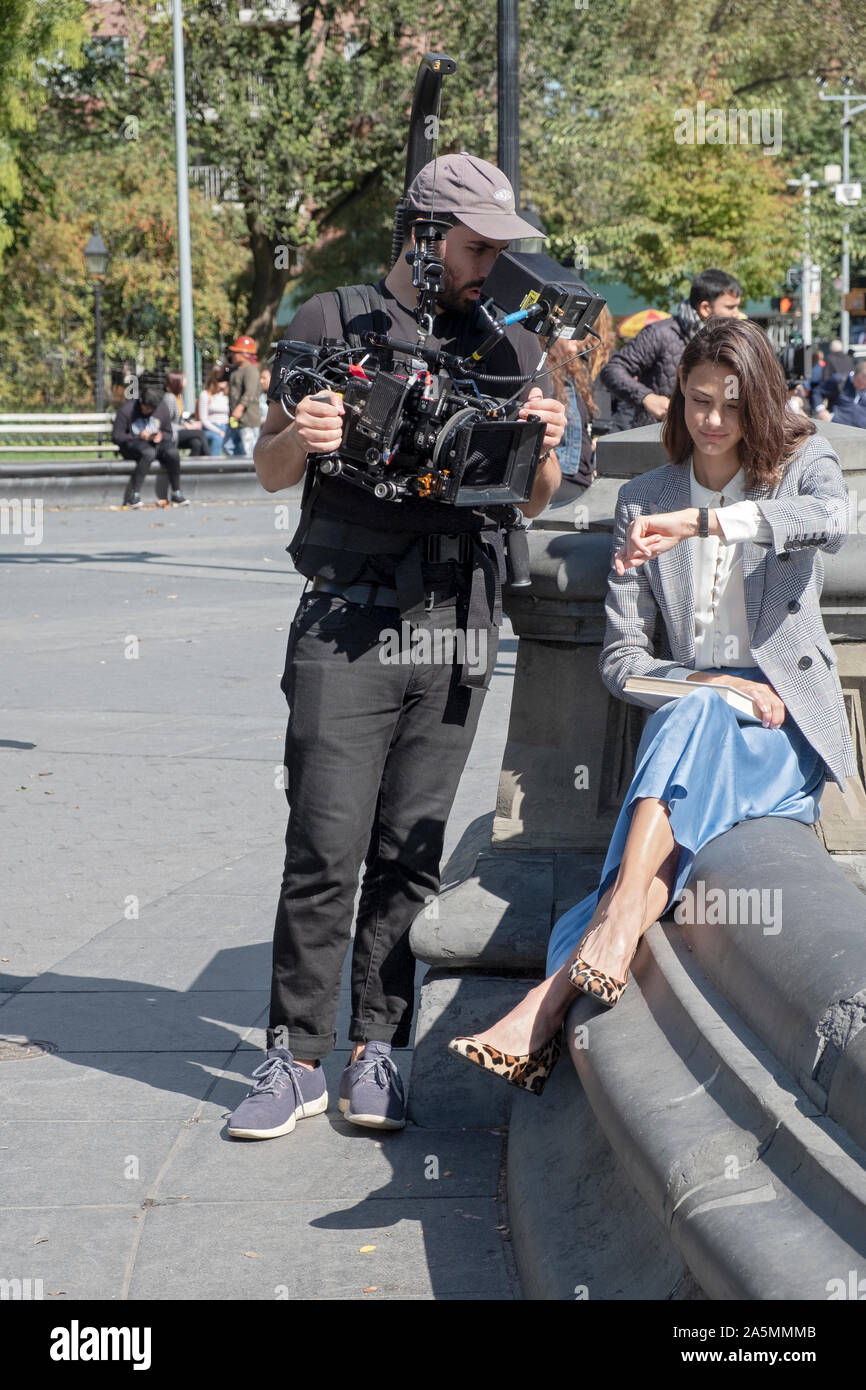 Un cineasta e un film di modello di ciò che appare essere un commerciale per gli orologi. A lui fontana in Union Square Park Foto Stock