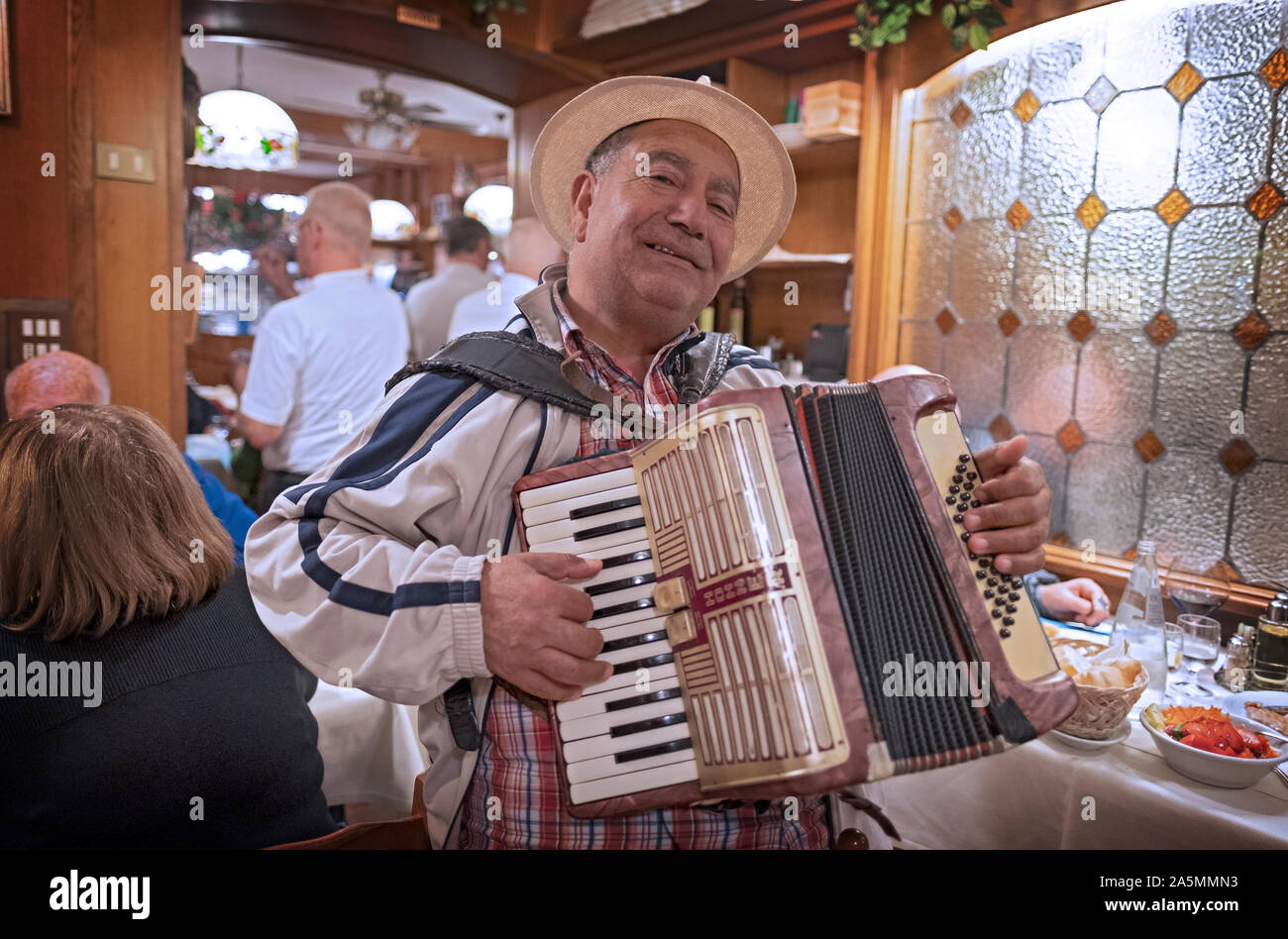 Un centro di età cantante fisarmonicista in un cappello di paglia esegue  per suggerimenti in un ristorante a venezia, Italia Foto stock - Alamy