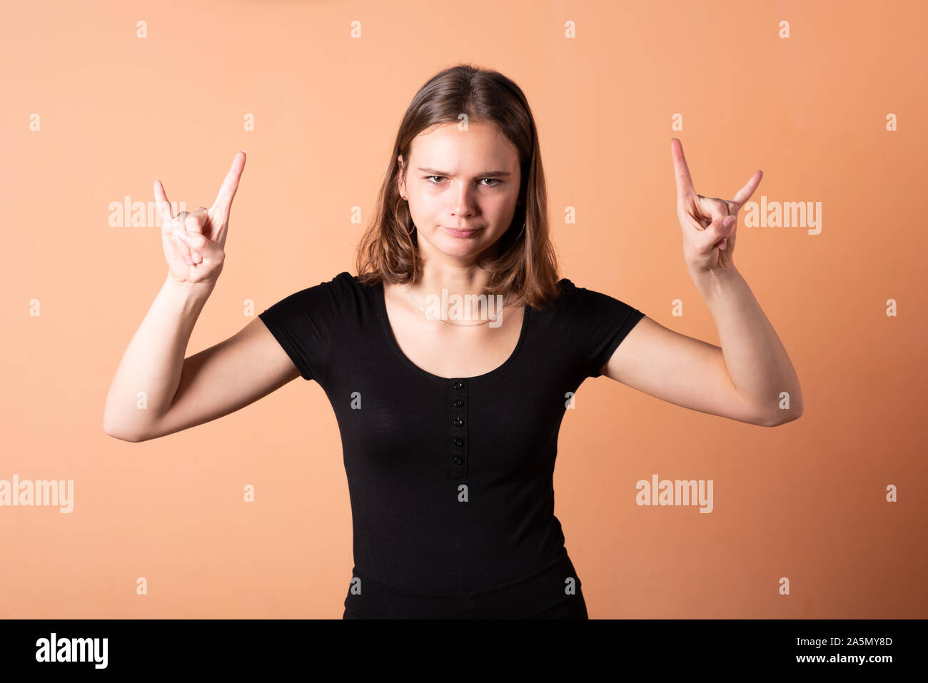 Una ragazza mostra un bilanciere di capra, su una luce sfondo arancione. Foto Stock