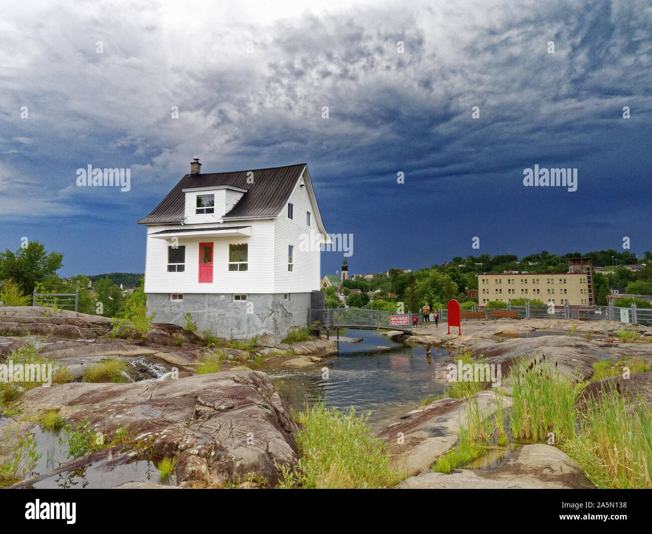 Il famoso little white house (La Petite Maison Blanche) in Saguenay che resistette alle inondazioni del 1996, con cielo tempestoso oltre Foto Stock