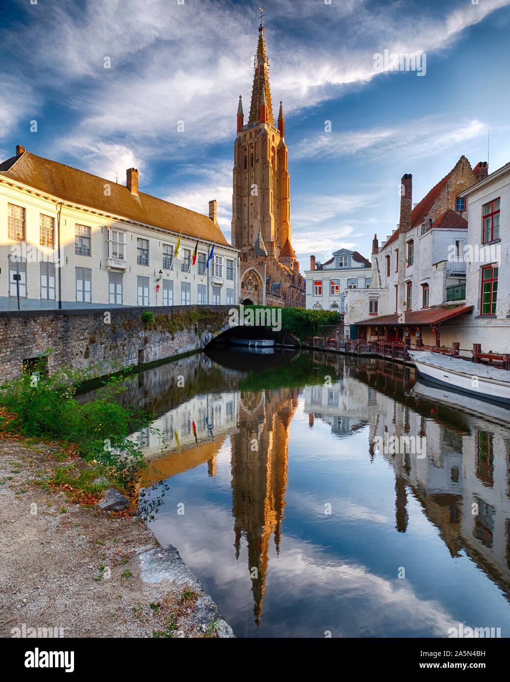 Scena tranquilla in Bruges con la Chiesa di Nostra Signora si riflette nel canale di Bruges, Belgio Foto Stock