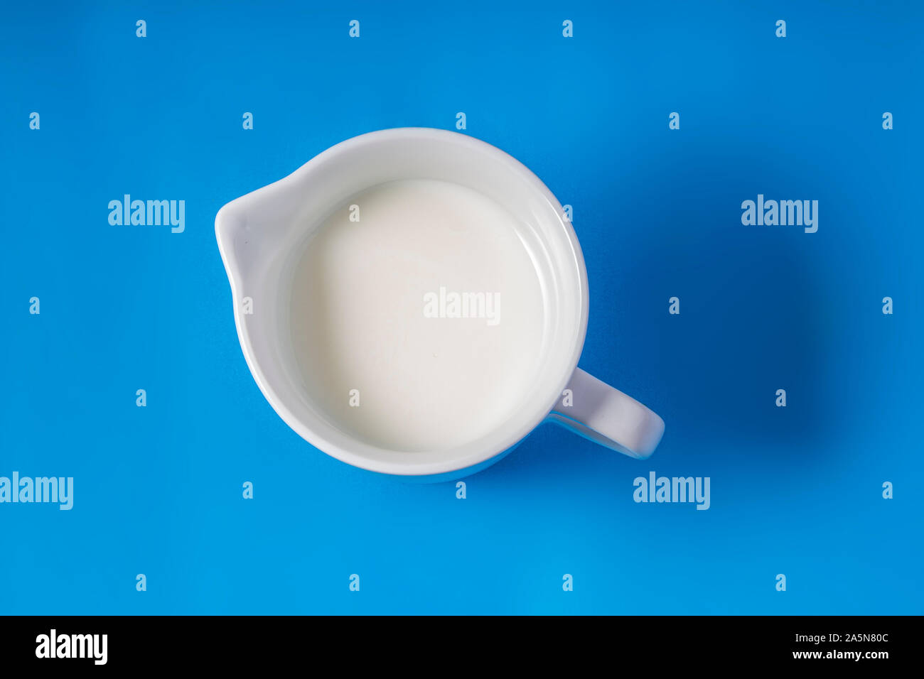 Bianco porcellana Creamer erogatore brocca con crema su uno sfondo blu Foto Stock