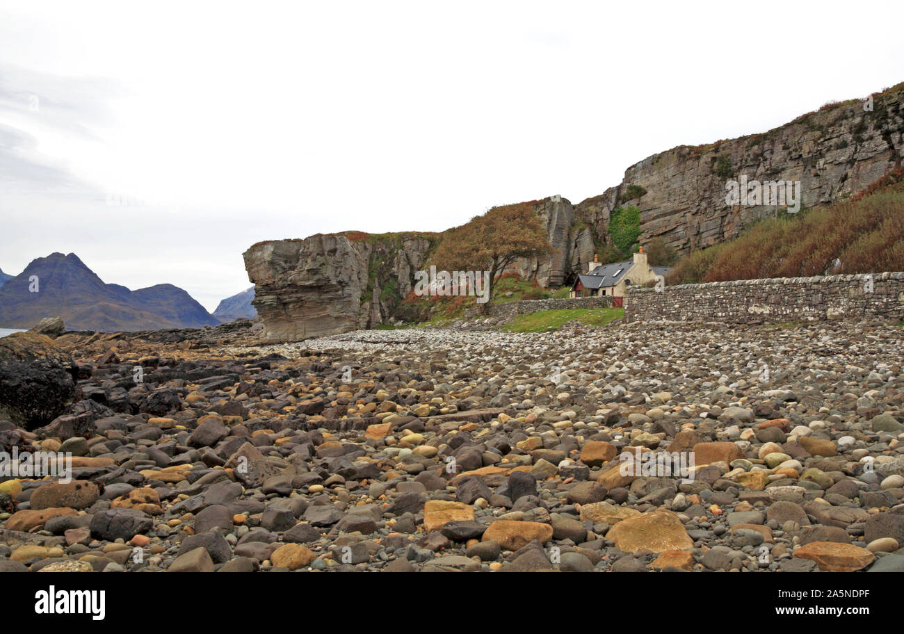 Una casa sopra la spiaggia al di sotto di un promontorio roccioso da Loch Scavaig a Elgol, Strathaird, Isola di Skye in Scozia, Regno Unito, Europa. Foto Stock