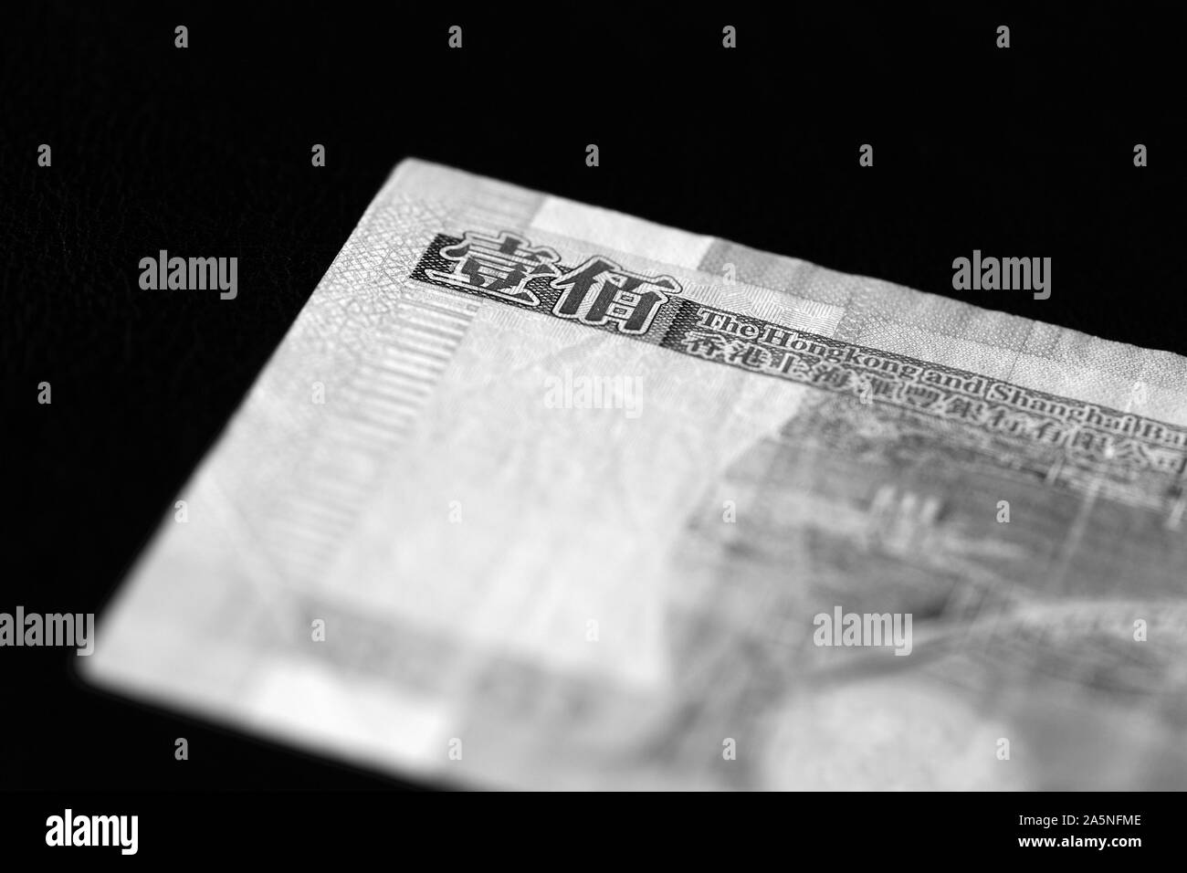 Un centinaio di dollari di Hong Kong banconota su sfondo scuro vicino. In bianco e nero Foto Stock