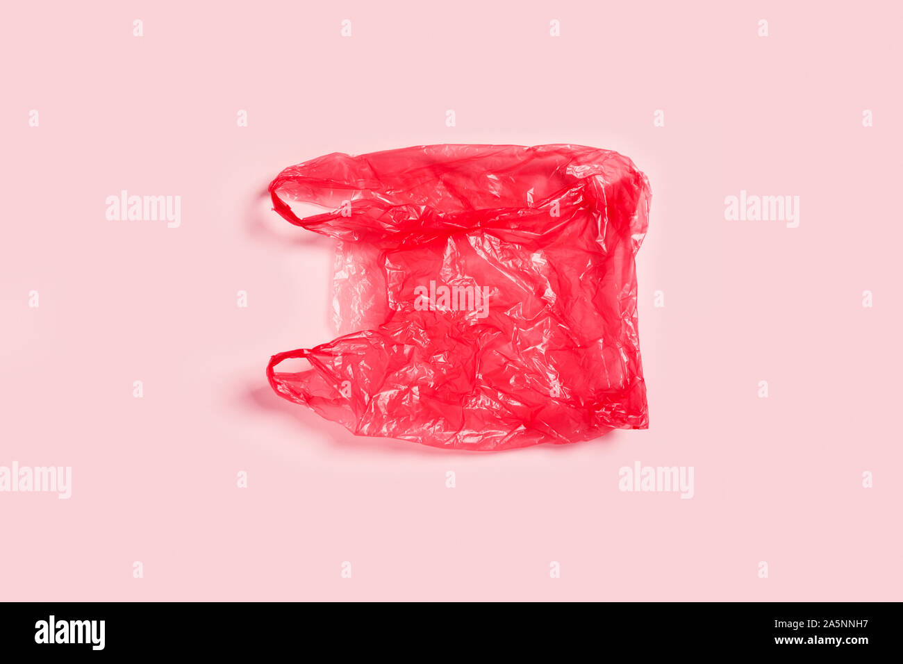Rifiuti Zero concetto. Plastica sacchetto rosso su sfondo rosa. Foto Stock