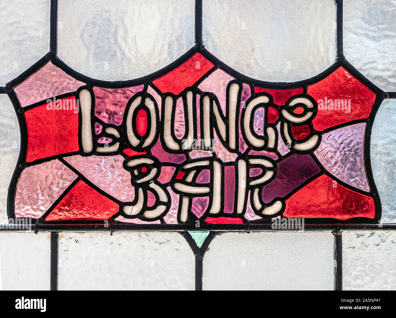 Finestra di vetro colorato che mostra LOUNGE BAR segno in un vecchio pub. Foto Stock