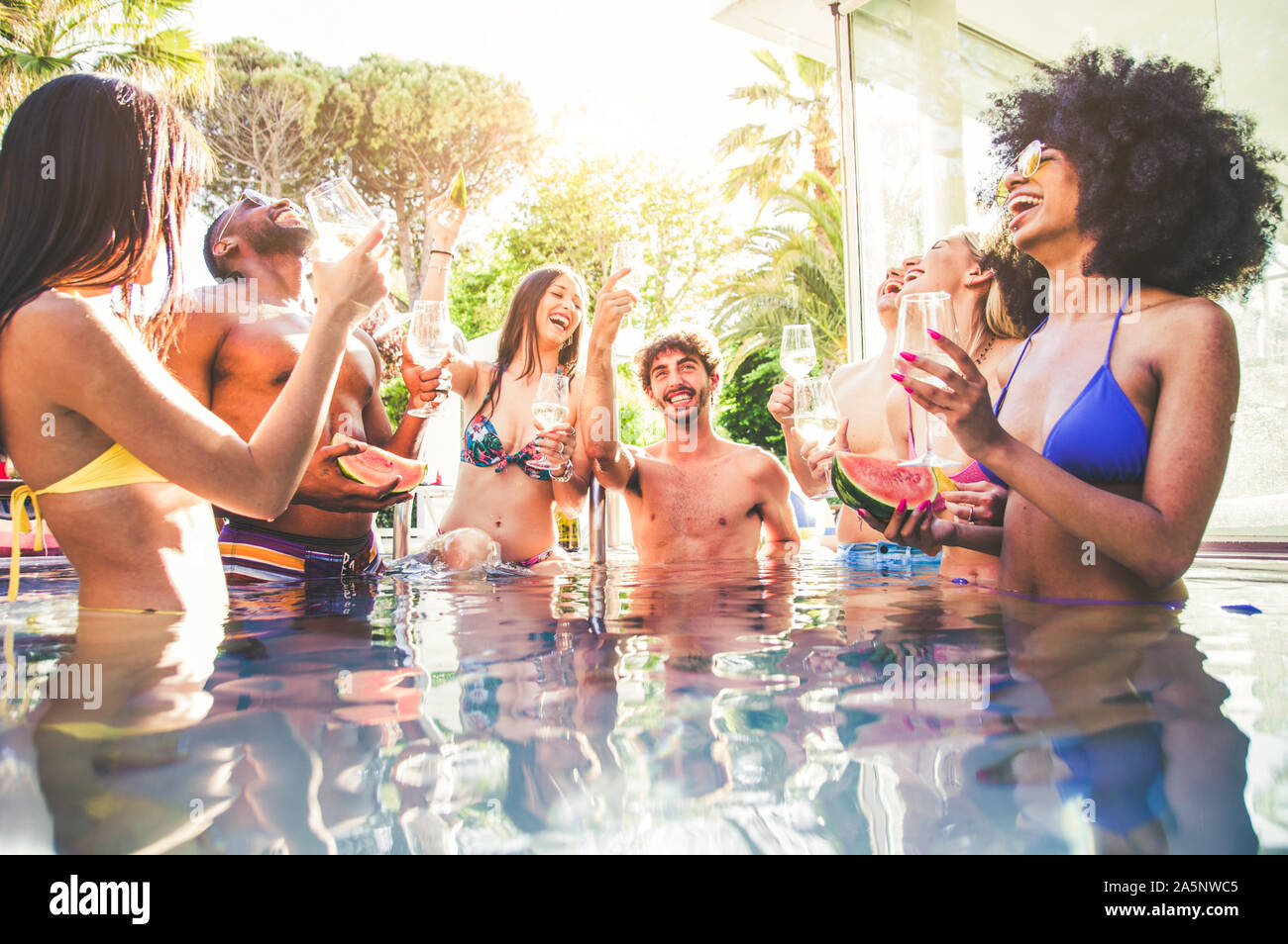 Multi-etnico gruppo di amici champagne di tostatura su un party in piscina Foto Stock