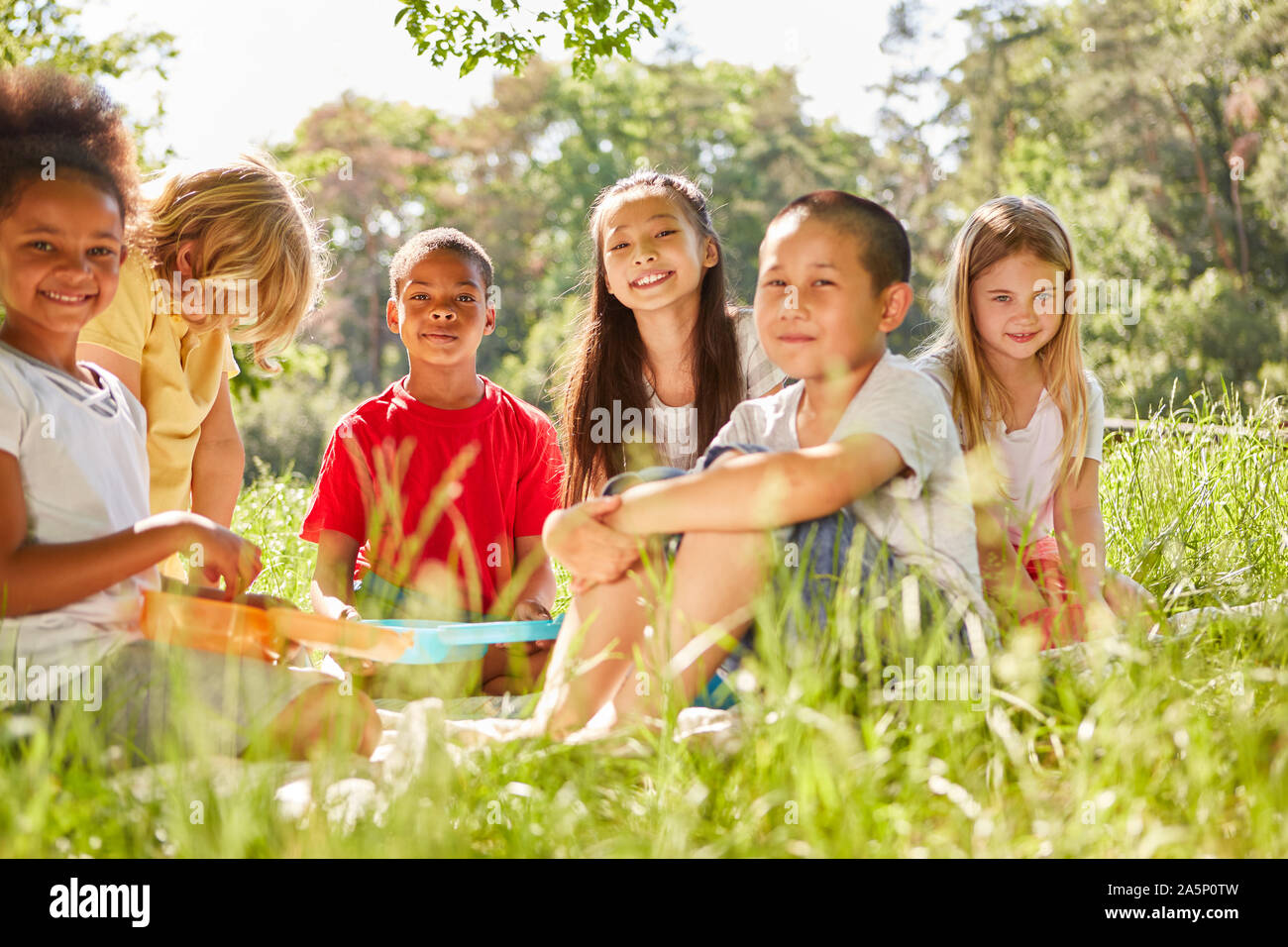 Multiculturale gruppo di bambini a un picnic su un prato in estate Foto Stock