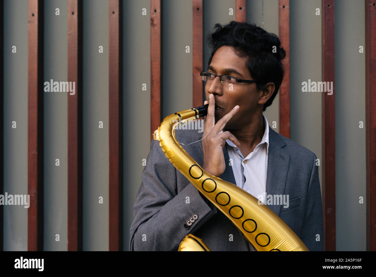 Funny bello uomo indiano con un colore dorato tubo gonfiabile Foto Stock