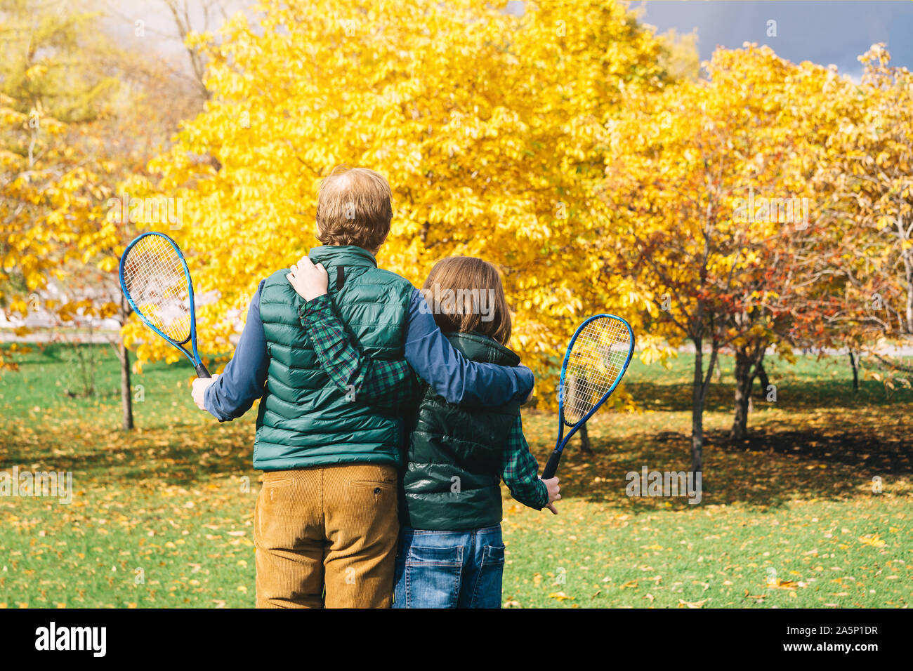 Un padre e figlio di età scolastica con badminton racchetta sta parlando Foto Stock