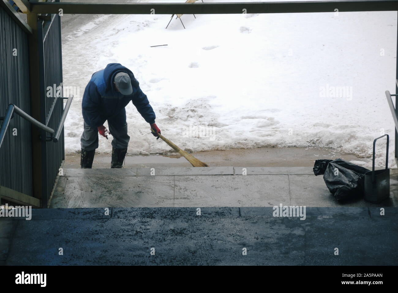 Lavoratore spazia fino nel cestino e neve in transizione Foto Stock