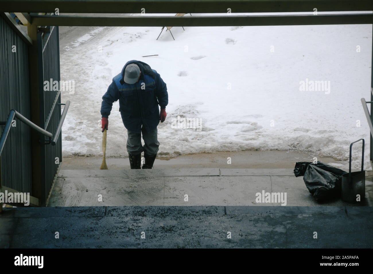 Lavoratore spazia fino nel cestino e neve in transizione Foto Stock
