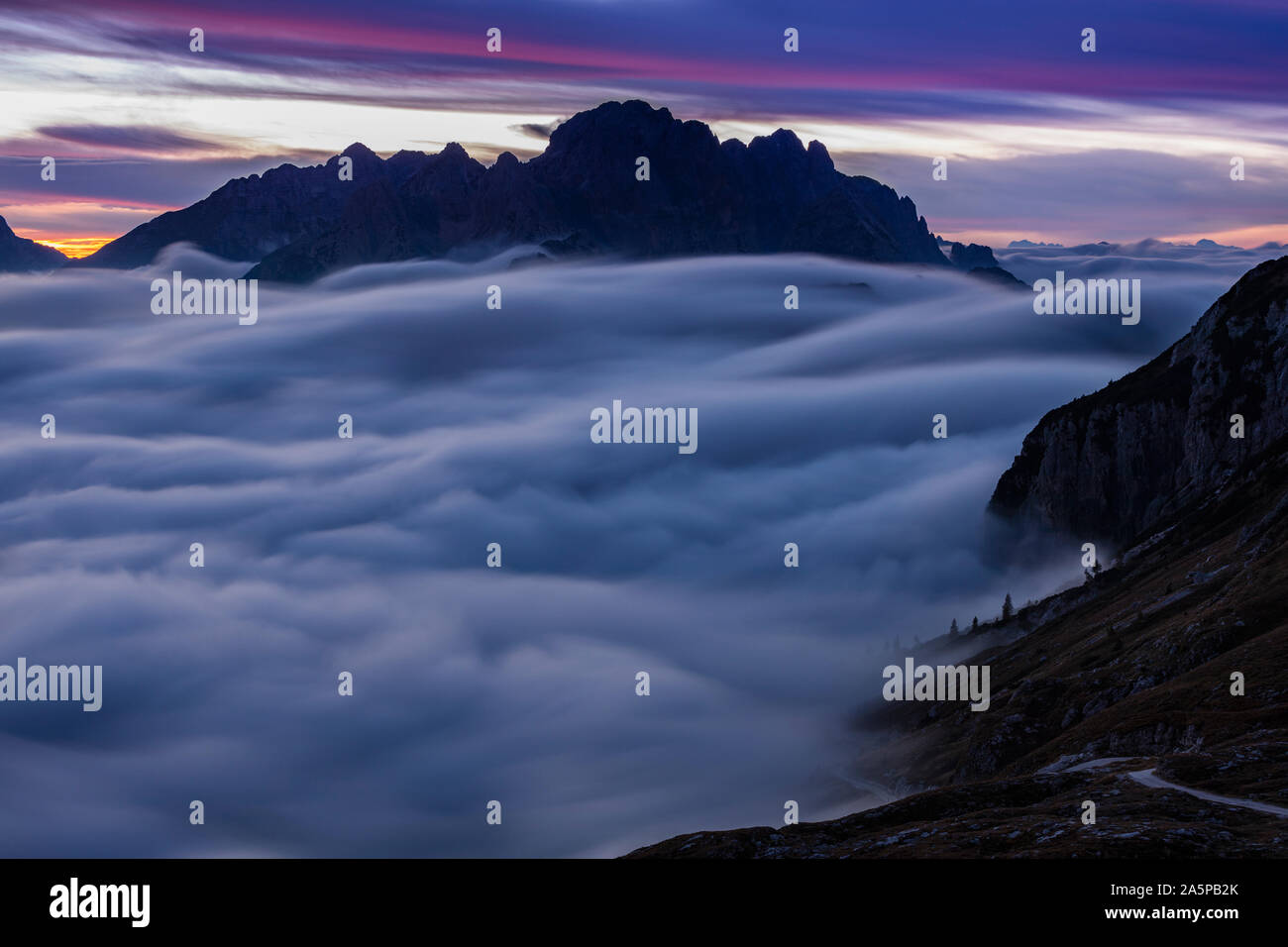 Nuvole che si muovono sulla cima di una montagna al tramonto Foto Stock