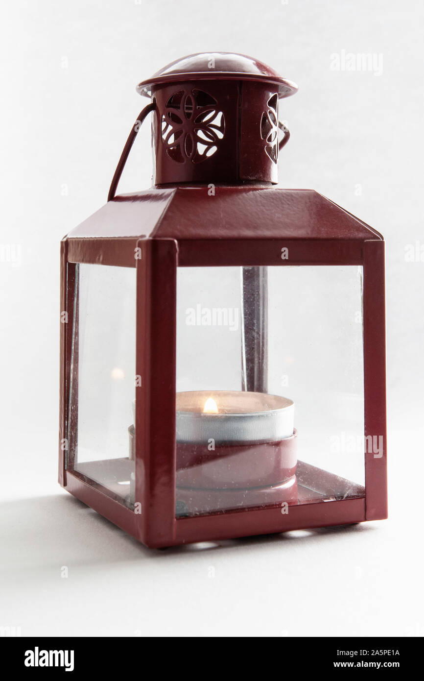 Lanterna rossa tenendo accesa una luce di tè set contro uno sfondo bianco Foto Stock