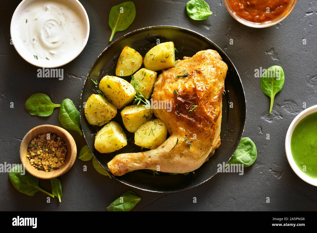 Pollo al Forno con la gamba di patate nere su sfondo di pietra. Piatto per la cena. Vista superiore, laici piatta Foto Stock