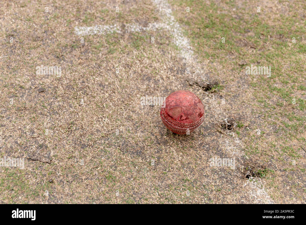 Una vista ravvicinata di un vecchio pozzo usato red cricket palla su un campo in erba Foto Stock