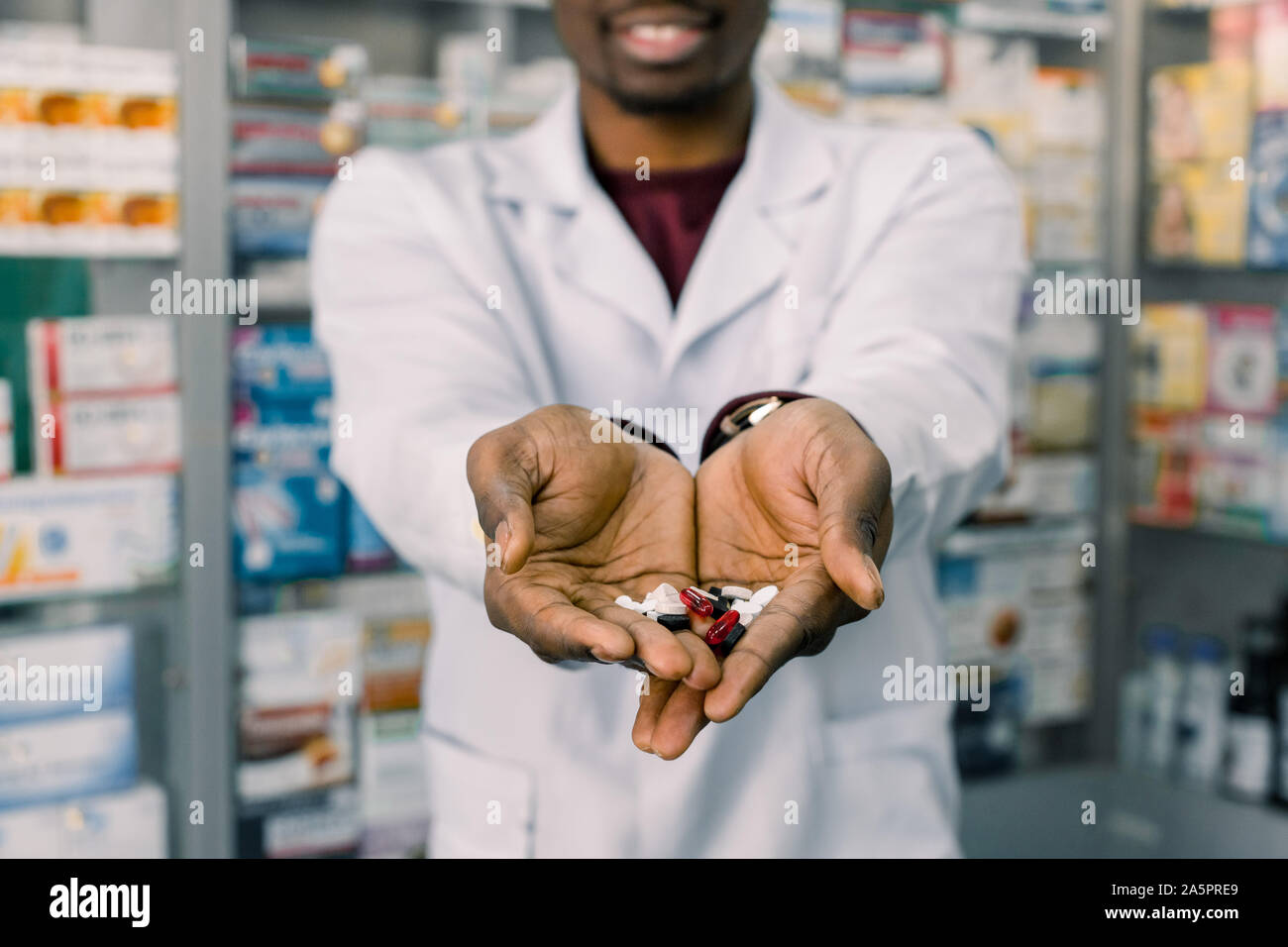 African-american farmacista uomo azienda compresse pillole nelle mani. Uomo con le mani in mano in possesso di una manciata di pillole medicinali per il trattamento di malattie Foto Stock