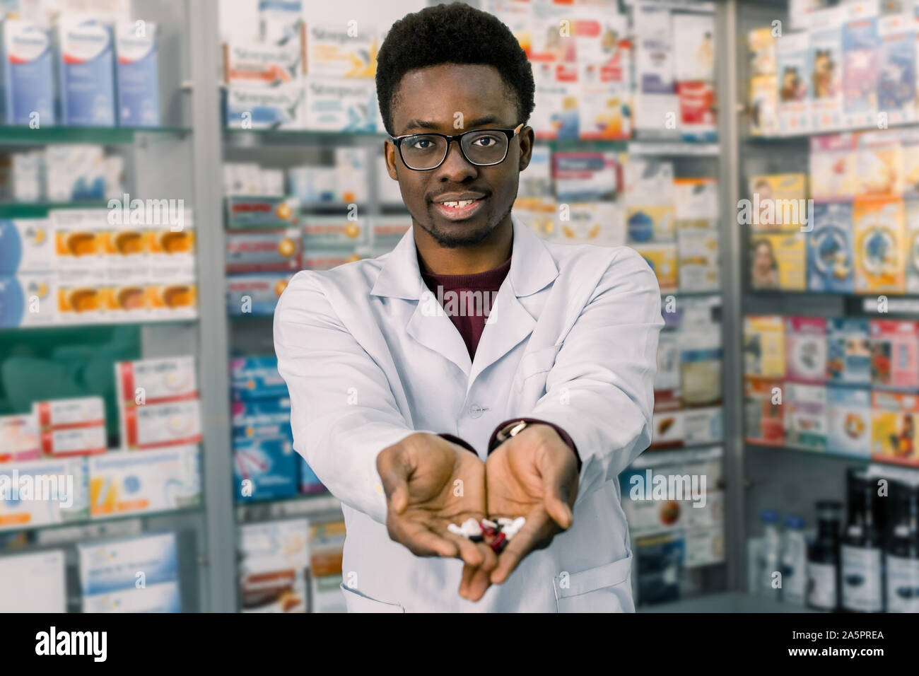 African-american farmacista uomo azienda compresse pillole nelle mani. Uomo con le mani in mano in possesso di una manciata di pillole medicinali per il trattamento di malattie Foto Stock