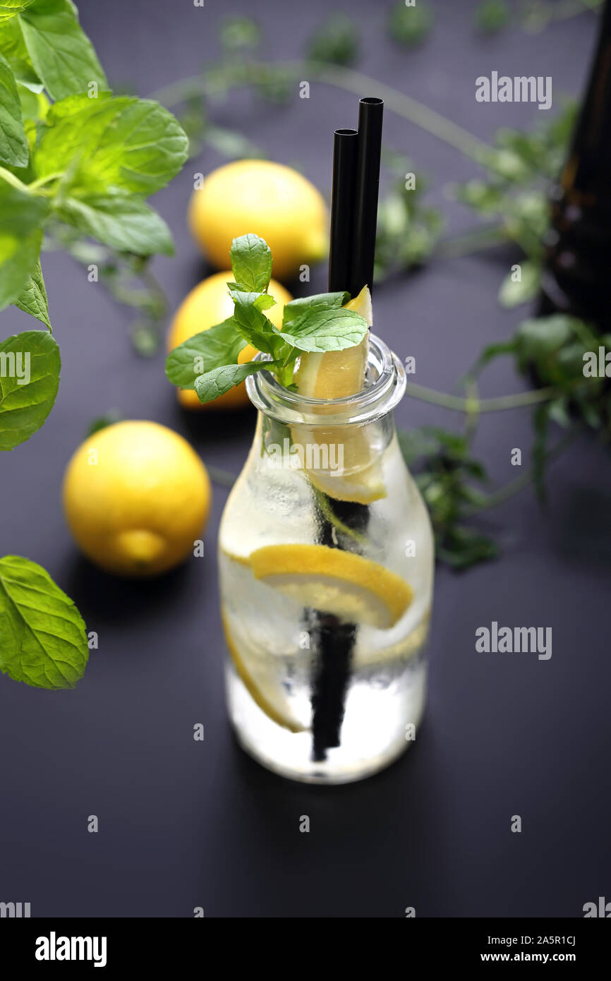 Acqua con limone, acqua in una bottiglia di vetro con limone e menta. Foto Stock