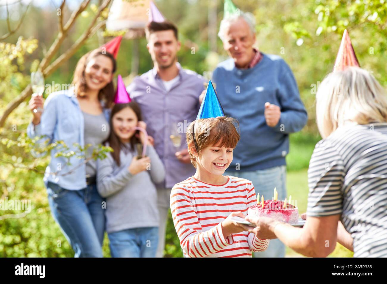 La nonna si congratula con il nipote bambino su una torta di compleanno a una festa in giardino Foto Stock
