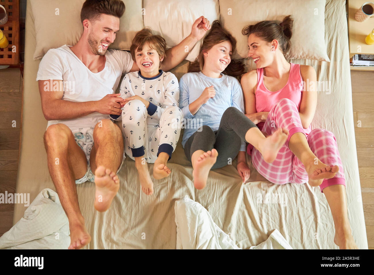 I genitori svolgono con i loro bambini nel letto e dare loro i piedi Foto Stock