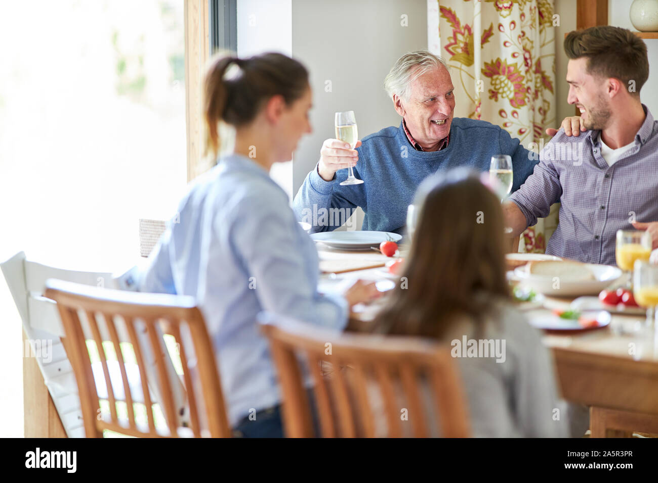 Nonno con vetro di champagne a pranzo o una festa in famiglia con i nipoti Foto Stock