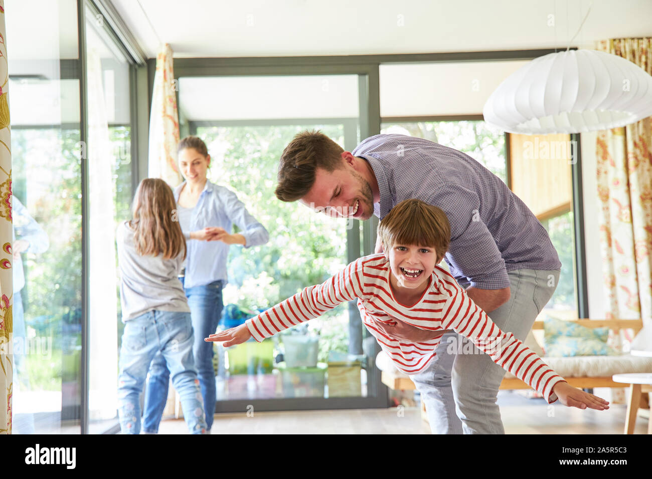 I genitori svolgono e divertitevi con i loro bambini felici nel soggiorno Foto Stock