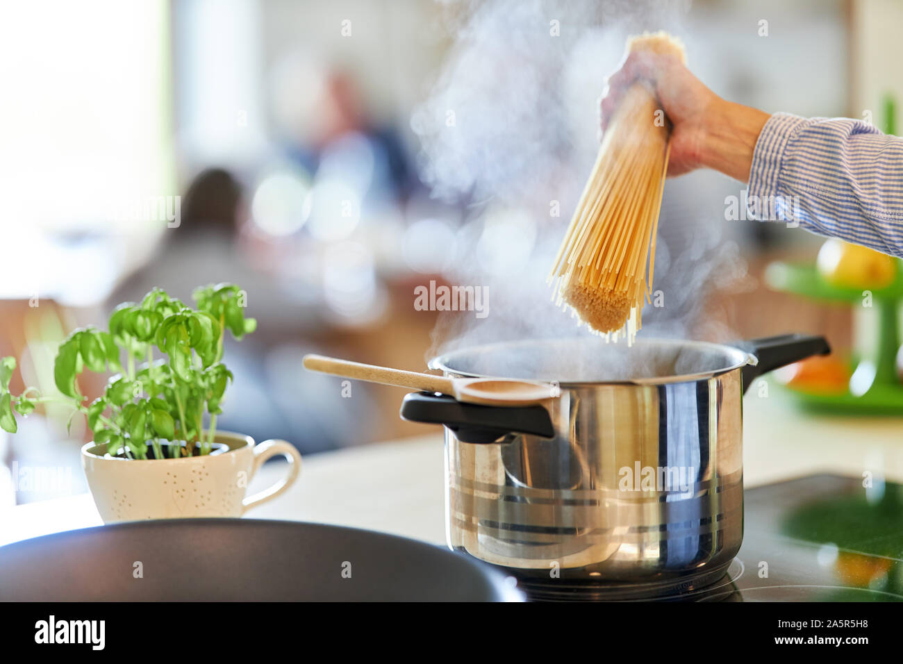 Mano di cuoco o cuocere gli spaghetti di contenimento sulla pentola con acqua bollente Foto Stock