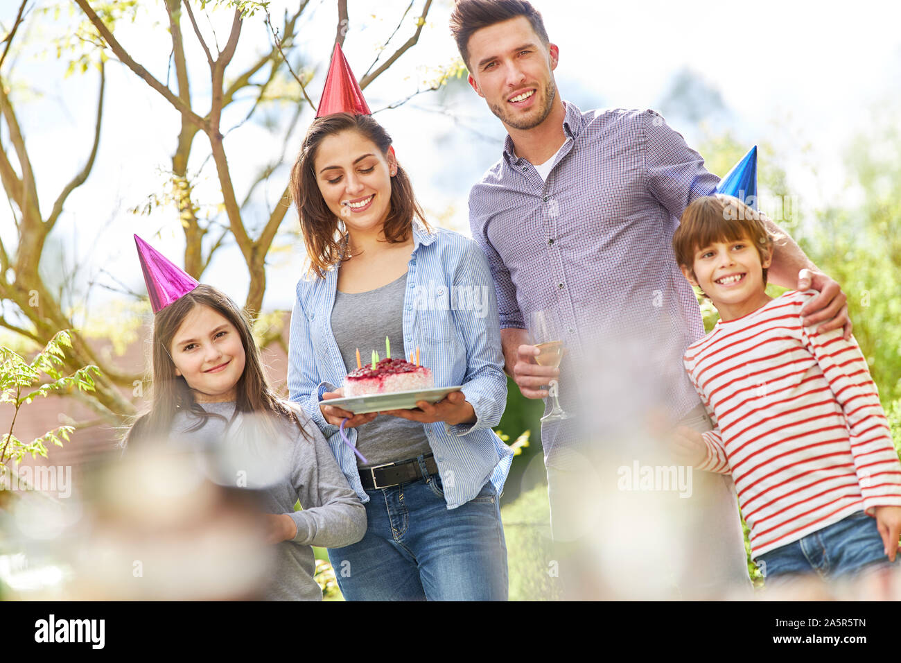 Famiglia con due bambini festeggiare il compleanno con la torta nel giardino in estate Foto Stock