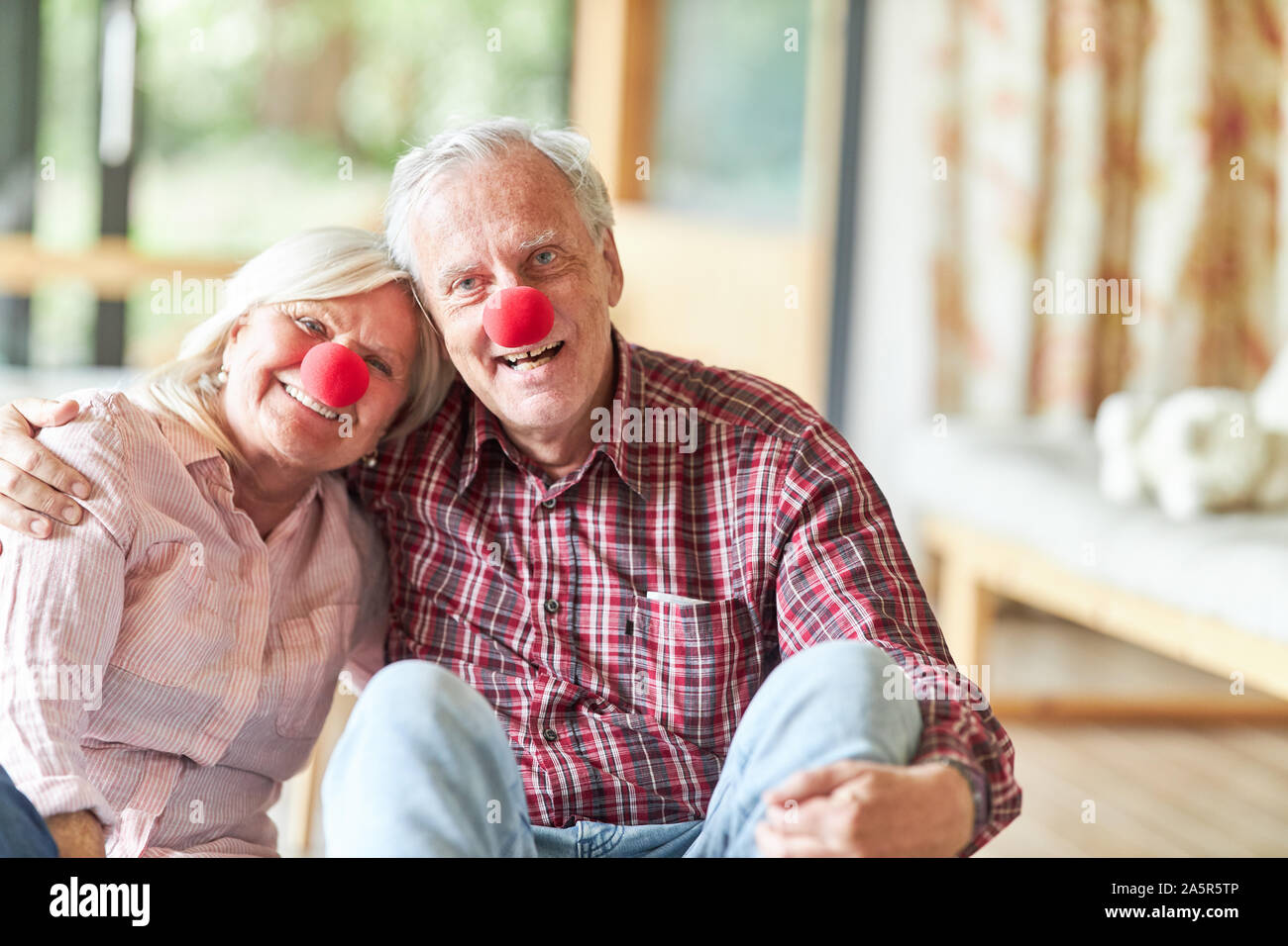 Sorridente coppia senior con red clown naso nel carnevale o il carnevale Foto Stock