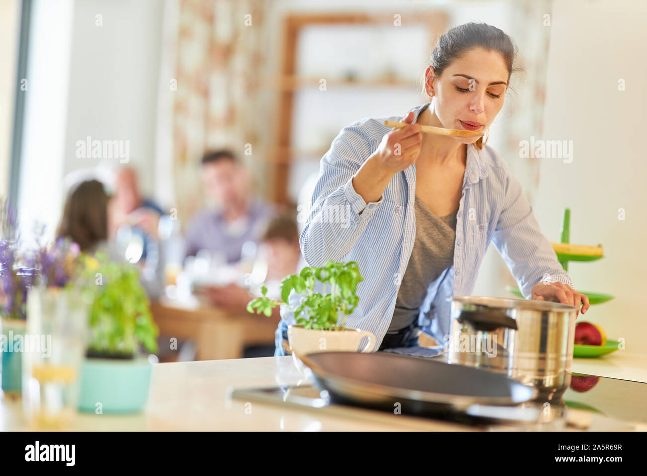 Giovane donna come un hobby cucinare durante la degustazione presso la stufa in cucina Foto Stock