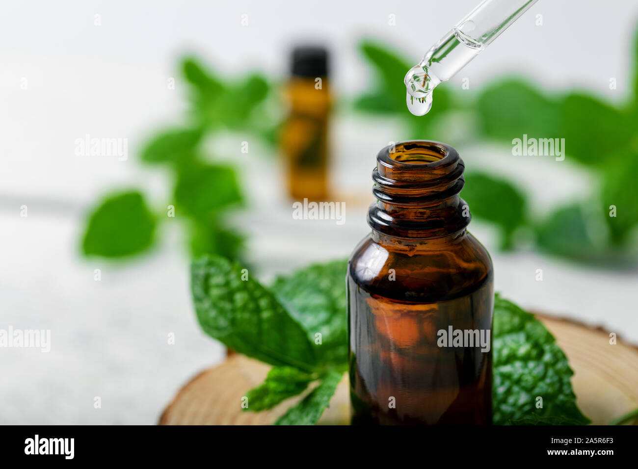 Olio essenziale di menta goccia cade da un contagocce nella bottiglia Foto Stock