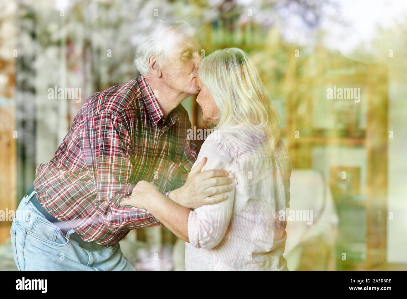 Senior dà la sua moglie un bacio sulla fronte come un segno di amore e di vicinanza Foto Stock