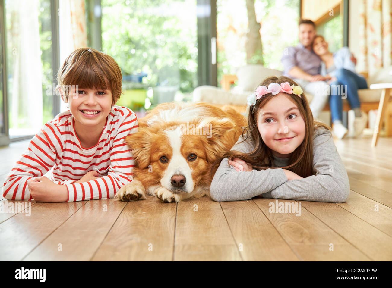 I gemelli figli giacciono insieme con il cane sul parquet nel soggiorno Foto Stock