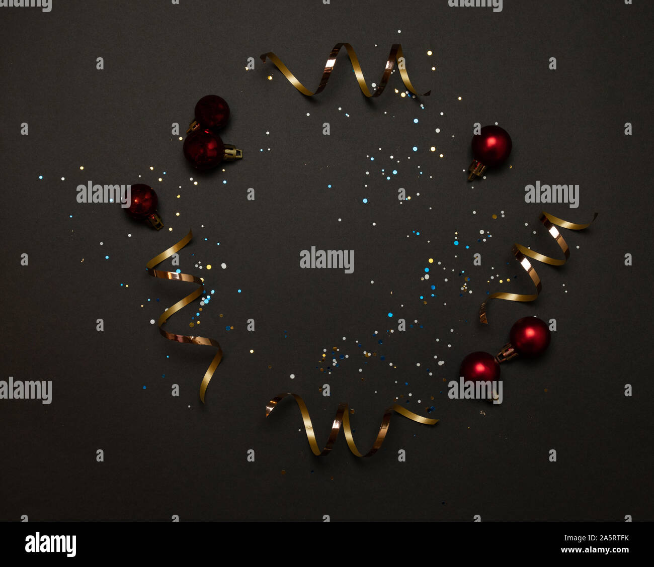 Natale e Anno Nuovo telaio di vacanza del classico rosso sfere smerigliato, glitter nastro color oro, coriandoli stelle su uno sfondo scuro Foto Stock