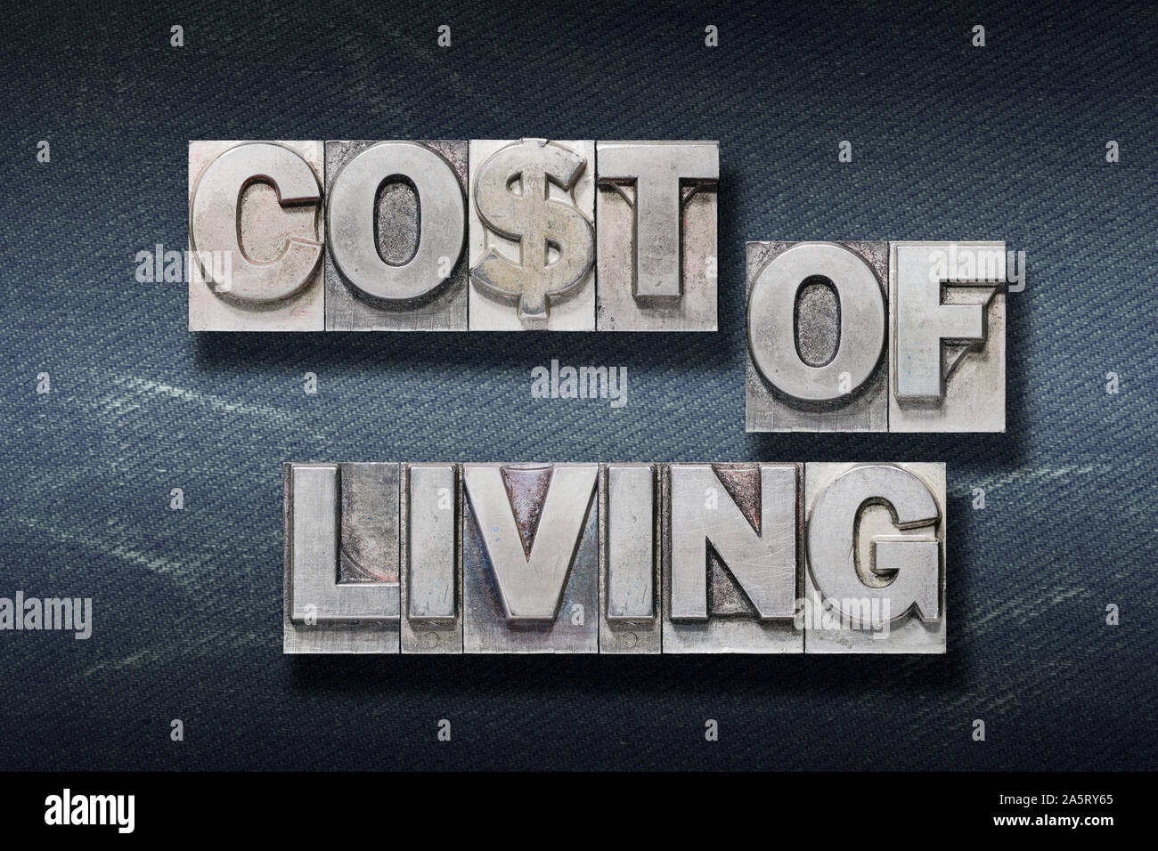 Costo della vita frase composta da polveri metalliche in rilievo sul jeans scuri sullo sfondo Foto Stock
