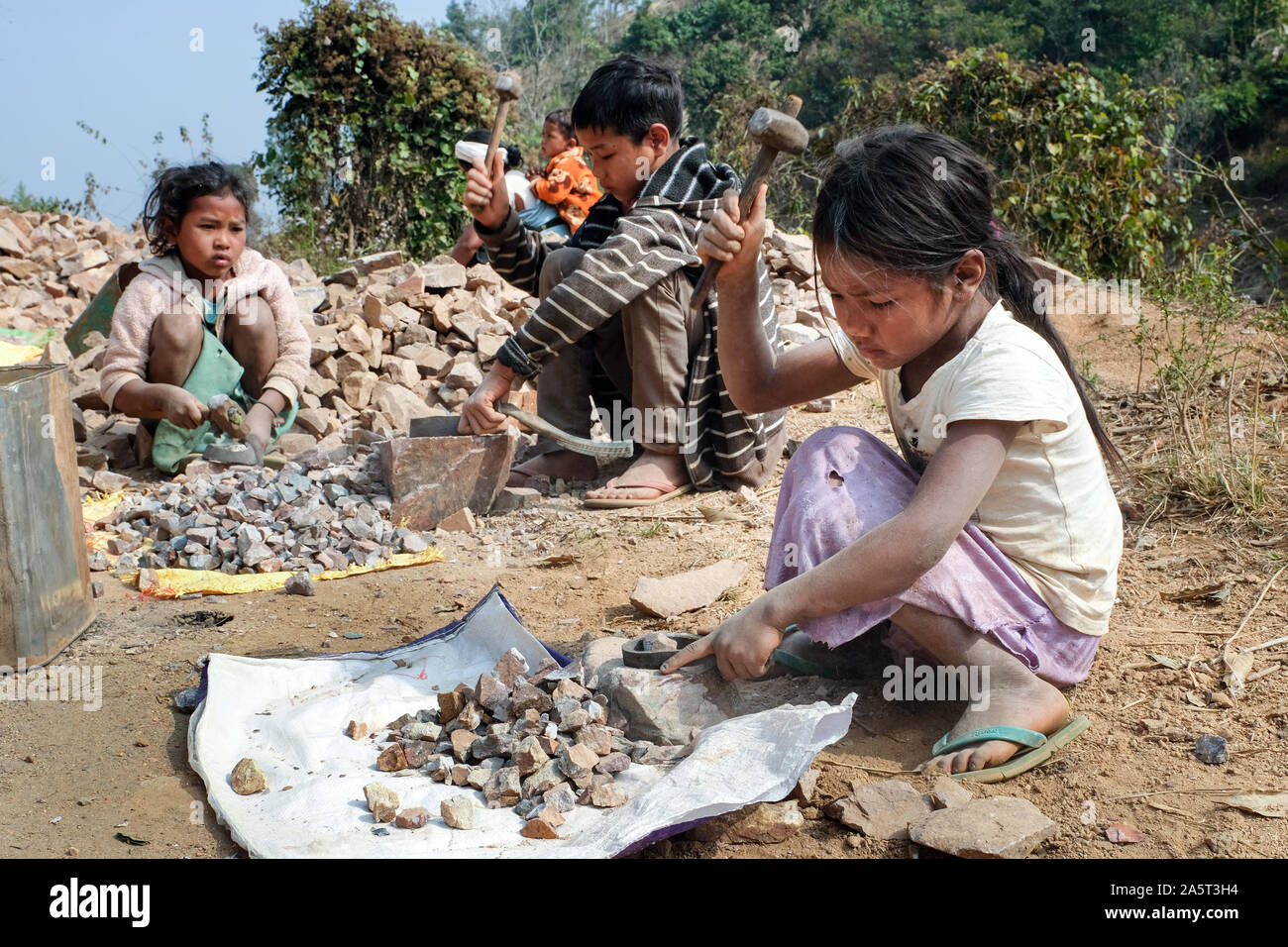I bambini sono impiegati per schiacciare pietre per costruzioni stradali (ragazze 6 e 7 anni, ragazzo 11 anni), Khasi Hills, Meghalaya, Indie, Asia Foto Stock