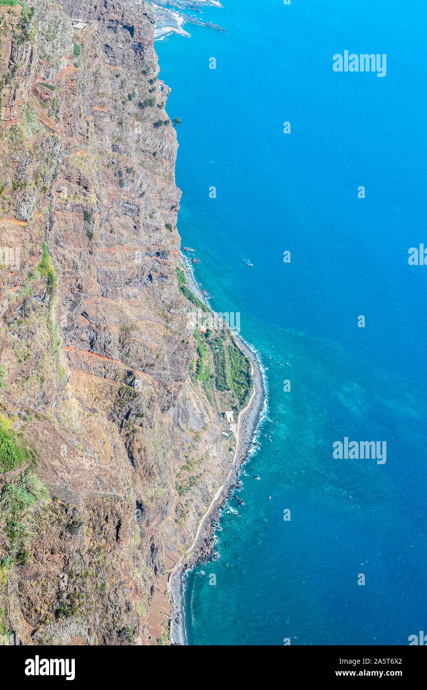 Vista aerea del blu oceano Atlantico e la costa di Madeira. Spiaggia di pietra e campi adiacenti sulla costa meridionale dell'isola di Madeira, Portogallo. Paesaggio di antenna, la splendida natura. Forme naturali. Foto Stock