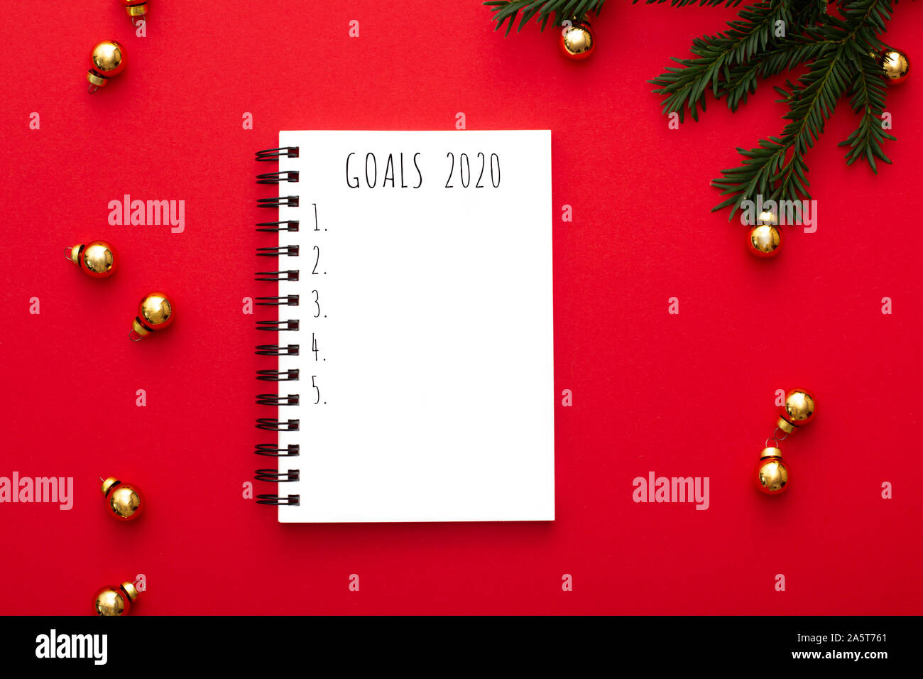 Notebook con 2020 degli obiettivi su sfondo rosso con golden decorazioni natalizie e verde abete il brunch. Vista dall'alto. Foto Stock