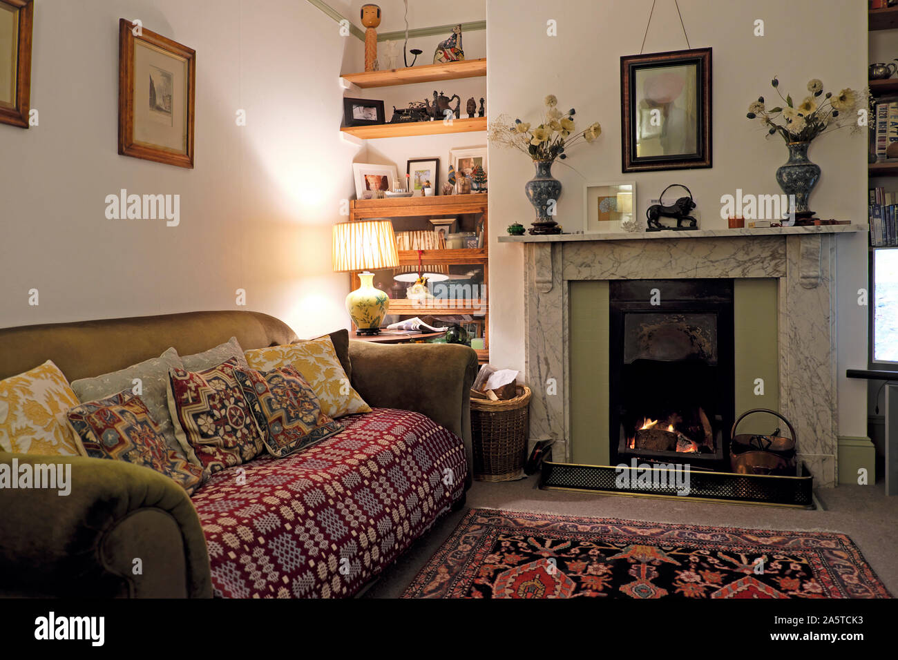 Soggiorno interno soggiorno in una casa vittoriana con camino in legno aperto focolare, tessuto coperta gallese in Inghilterra Regno Unito Gran Bretagna KATHY DEWITT Foto Stock