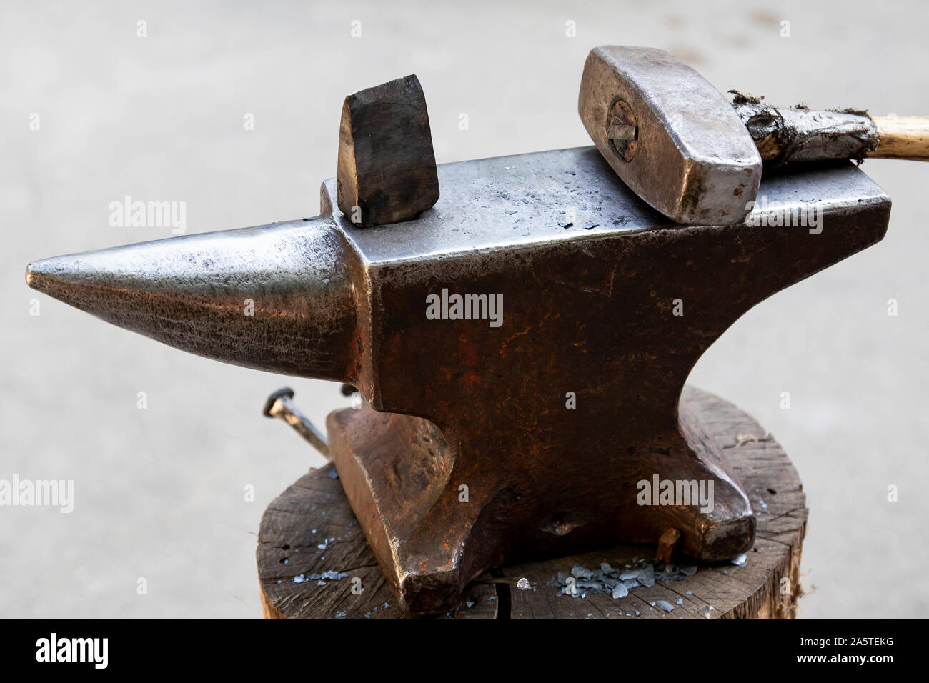 Un martello e un oggetto di metallo su una incudine. Gli strumenti e gli oggetti di metallo utilizzato dal fabbro in un negozio di fabbro ferraio. Foto Stock